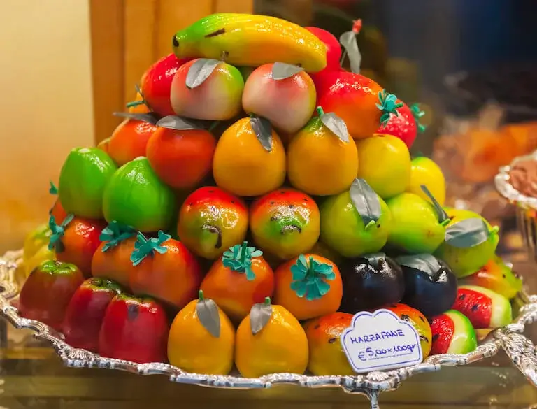Marzipan shaped and painted to look like fruits, stacked in a towering display.