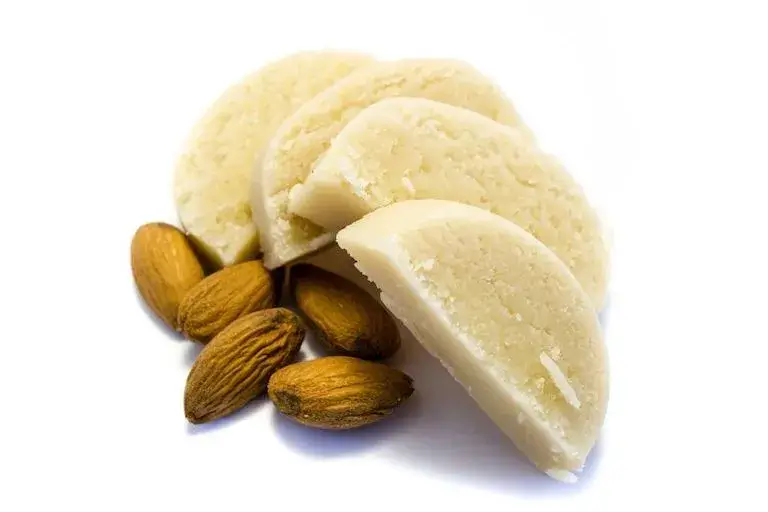 Slices of marzipan alongside whole blanched almonds