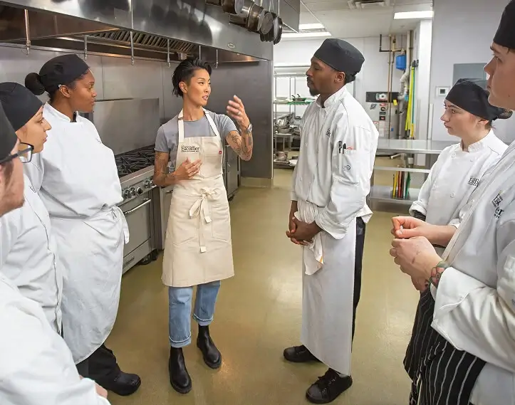 Escoffier chef-in-residence Kristen Kish speaks to Escoffier culinary students in a commercial kitchen on the Escoffier campus
