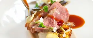 Sliced meat with roasted vegetables and rich brown sauce garnish