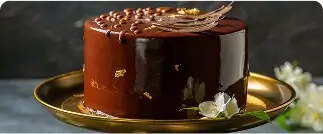 Glossy chocolate cake with gold leaf decoration on golden plate