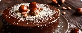 Chocolate cake topped with chestnuts and powdered sugar on wooden surface