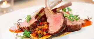 Sliced rack of lamb with herbs, vegetables, and red sauce