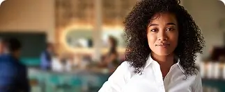 Woman with curly hair standing in a restaurant smiling