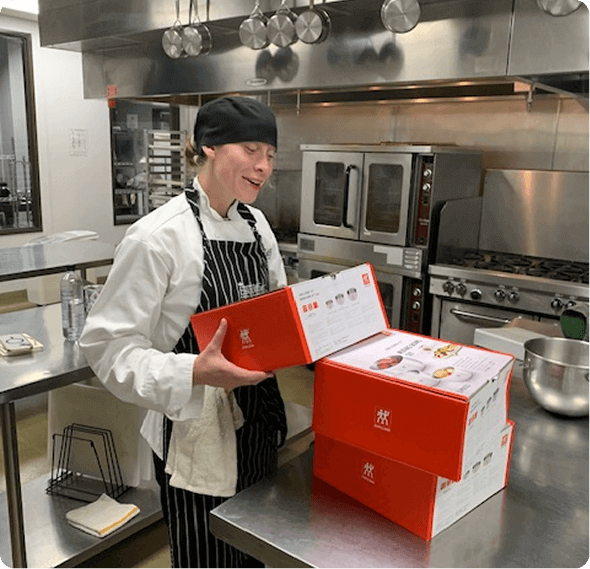 Escoffier culinary student unboxing a knife set in a kitchen classroom