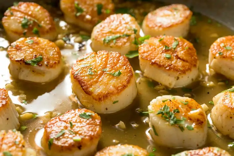 Pan of seared scallops with golden-brown crusts.