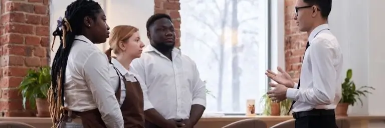 Hotel food service team meeting with manager in a professional setting.