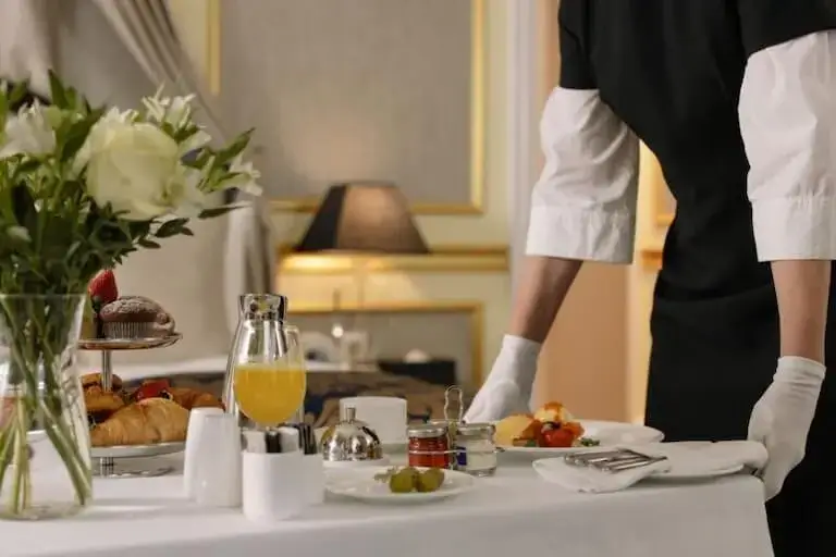 Server preparing elegant table setting for hotel dining service.