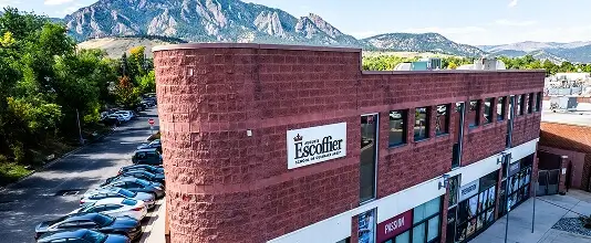 Exterior view of the Auguste Escoffier School of Culinary Arts Boulder campus with mountains in the background