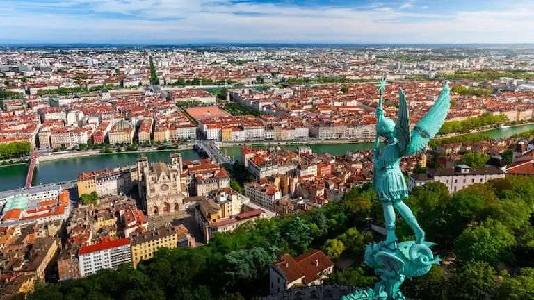 A panoramic aerial view of Lyon, France, showing buildings, the river, and city landmarks.