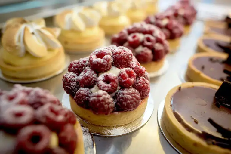 Assorted fruit tarts displayed in a bakery case.