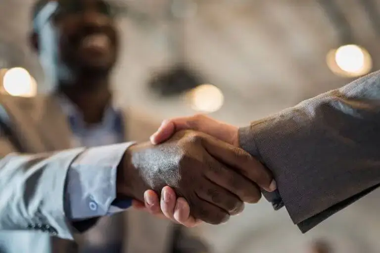 Two people shaking hands in a professional setting.