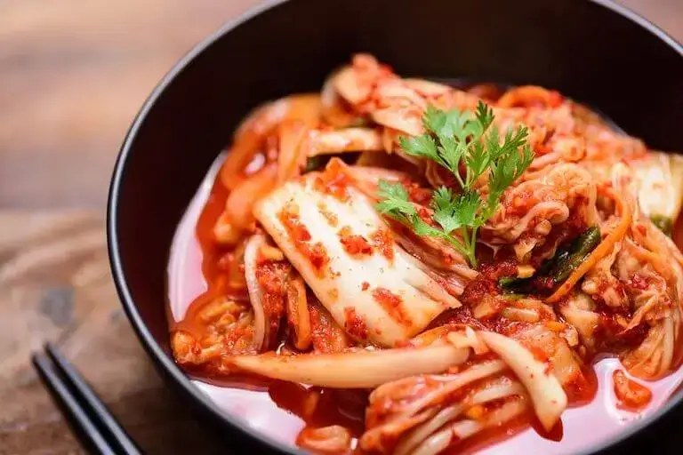 Kimchi cabbage in a bowl with chopsticks.
