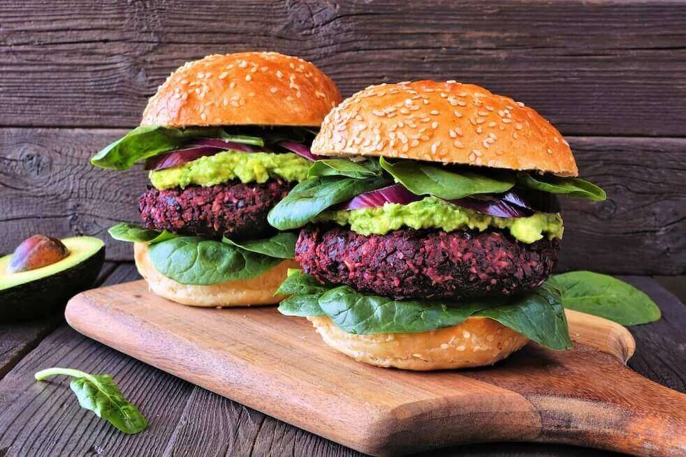 Two vegan beet burgers on a wooden cutting board