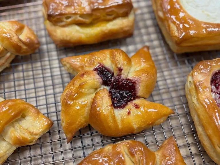 Glazed pastries with berry filling created by Escoffier Baking and Pastry graduate Emma R arranged on a cooling rack.