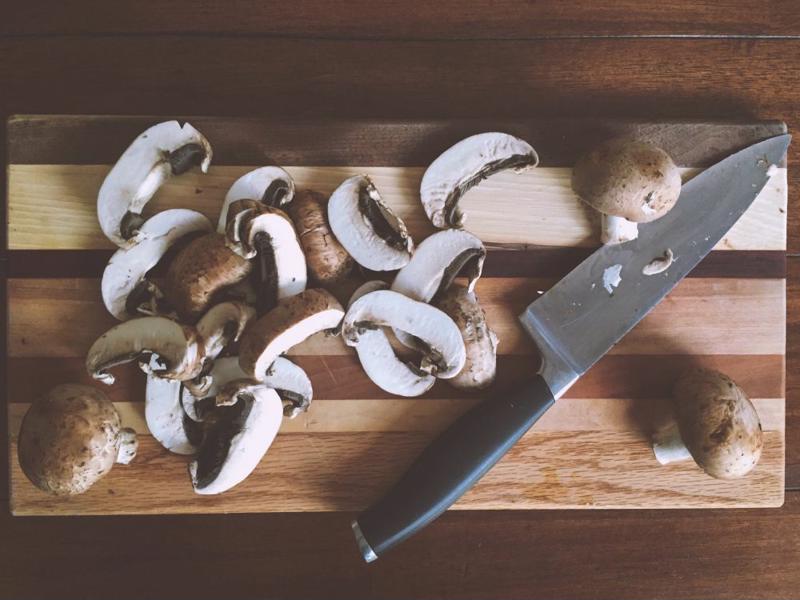 Cutting board with mushrooms and chef's knife.