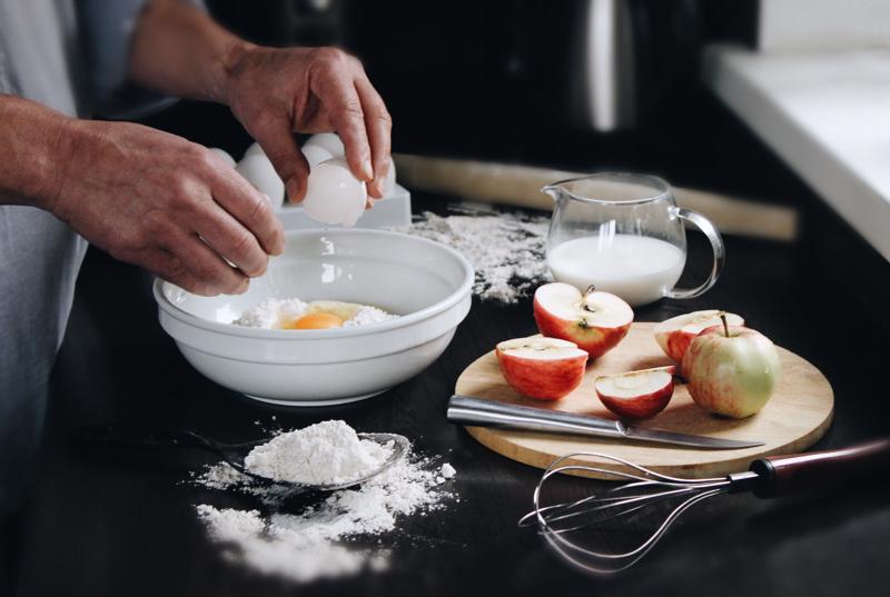 Baker cracking an egg in a bowl