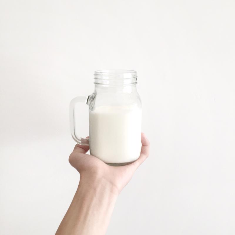 A person holds up a jar of milk.