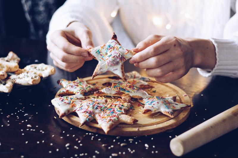 A pastry chef decorates desserts shaped like stars and trees.