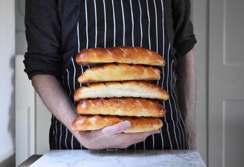 Baker holding freshly-baked loaves of bread