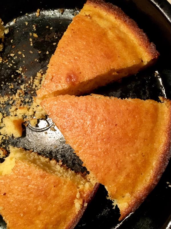 A skillet with wedges of cornbread inside.
