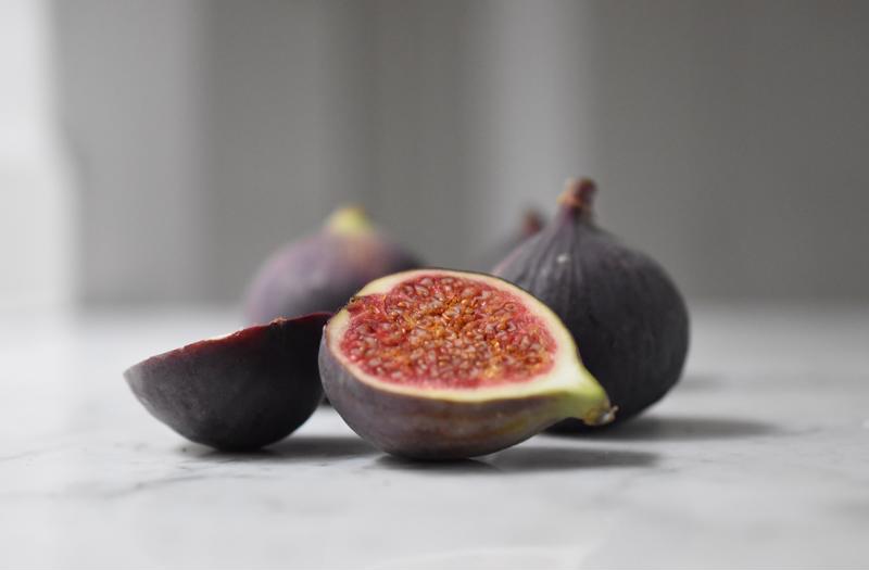 A close up of a halved fig with more figs in the background.