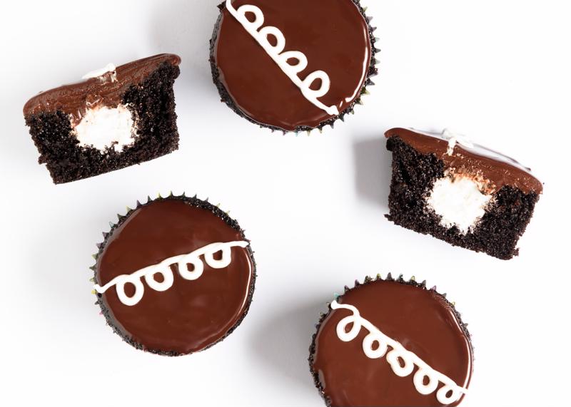 A group of chocolate cupcakes on a neutral background.