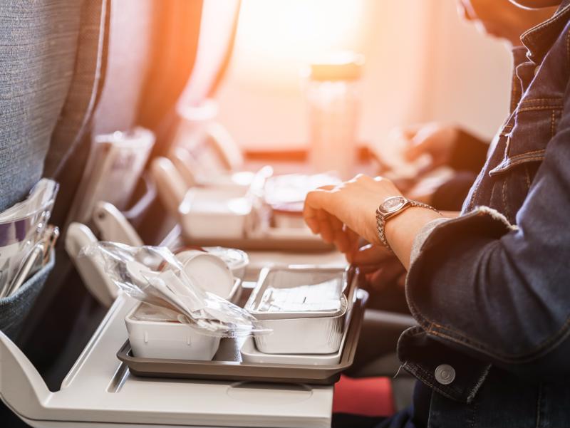 A person eating a meal on an airplane.