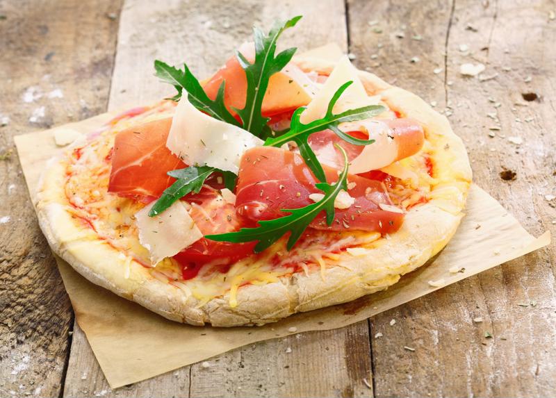 A small pizza sitting on a wooden table.