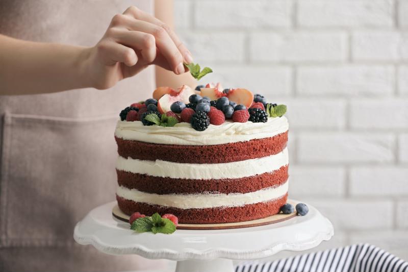 A chef placing a small garnish on a layer cake.